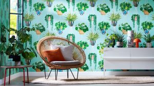 A modern room with a chair in front of a patterned wallpaper featuring white hanging planters.